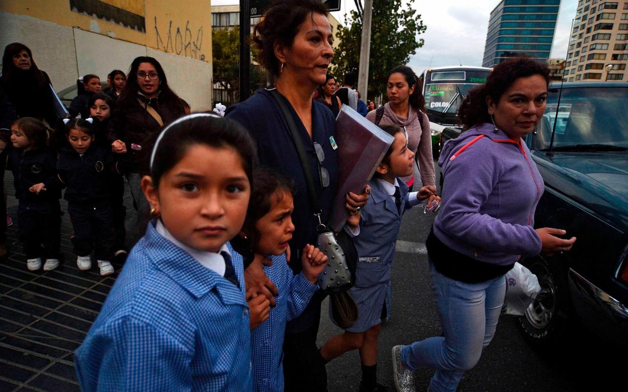 Women and schoolchildren evacuate a building during the quake in Vina del Mar, Chile - AFP