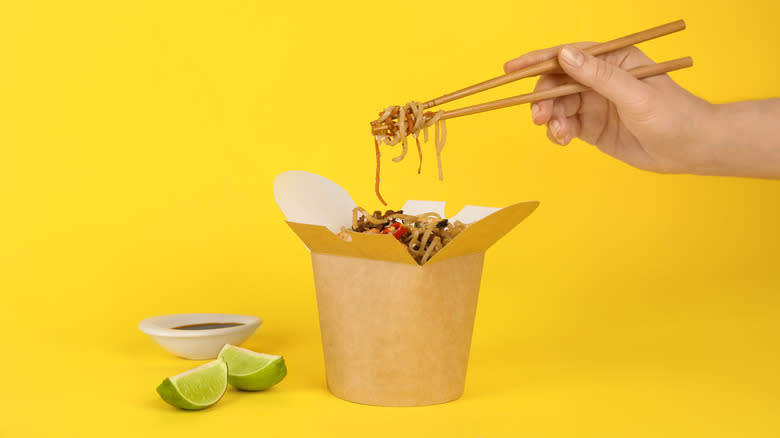 hand using chopsticks over takeout