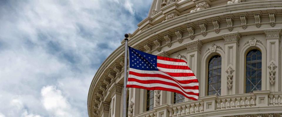 Washington DC Capitol with waving flag on cloudy day