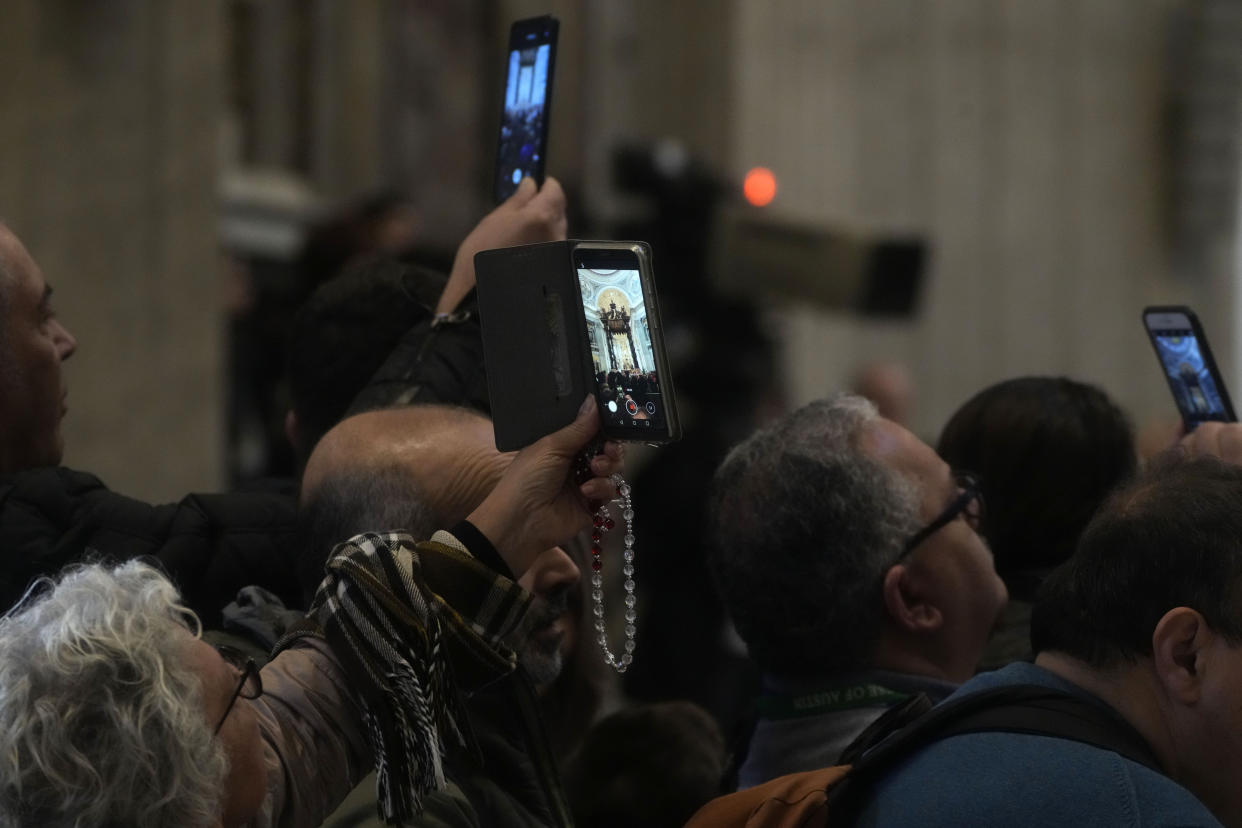 People film the body of late Pope Emeritus Benedict XVI lied out in state inside St. Peter's Basilica at The Vatican, Wednesday, Jan. 4, 2023. Pope Benedict, the German theologian who will be remembered as the first pope in 600 years to resign, has died, the Vatican announced Saturday, Dec. 31, 2022. He was 95.(AP Photo/Gregorio Borgia)