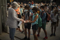 Students wearing face masks to prevent the spread of coronavirus disinfect their hands before entering their school in Barcelona, Spain, Monday, Sept. 14, 2020. Students in Catalonia and Murcia returned to the classrooms for the first time since schools closed due to the coronavirus pandemic. (AP Photo/Emilio Morenatti)