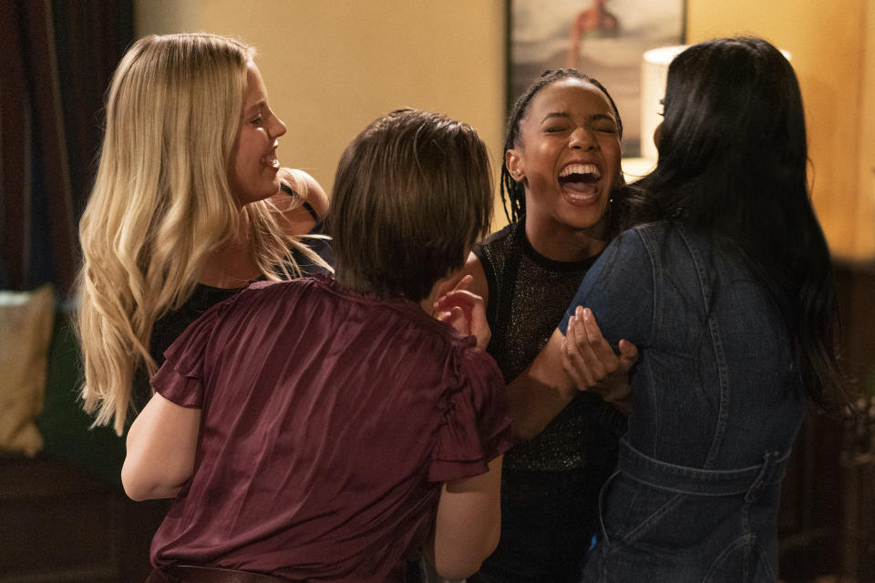 Four female college freshmen hug while laughing.