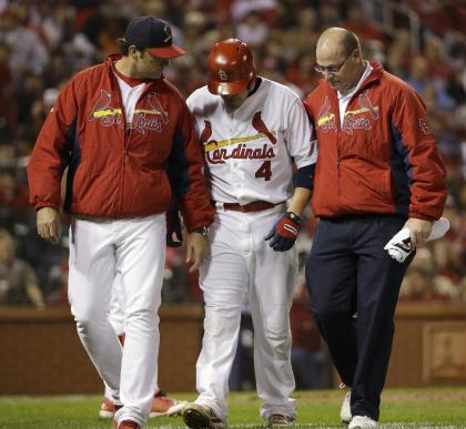 Yadier Molina, center, is helped off the field after straining his oblique Sunday night. (AP)