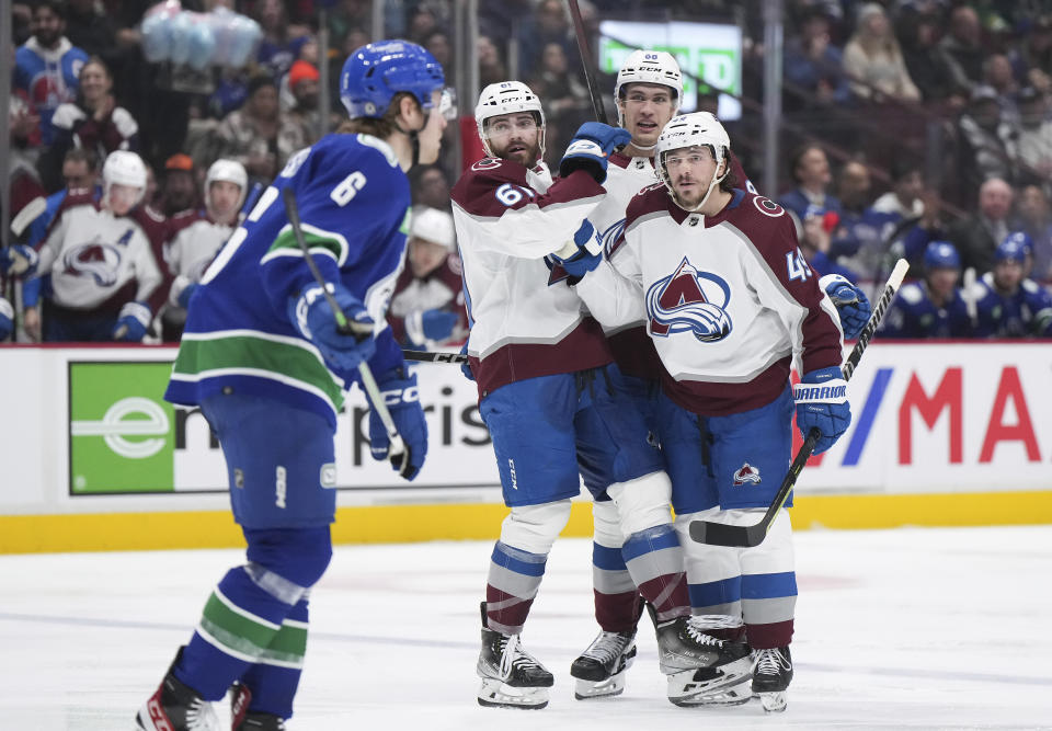 Colorado Avalanche's Samuel Girard (49), Martin Kaut (61) and Andreas Englund celebrate Girard's goal as Vancouver Canucks' Brock Boeser skates past during the second period of an NHL hockey game Thursday, Jan. 5, 2023, in Vancouver, British Columbia. (Darryl Dyck/The Canadian Press via AP)