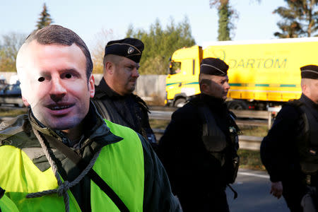 A man wears a mask with the likeness of French president Emmanuel Macron as people take part in the nationwide yellow vests demonstrations, a symbol of French drivers' protest against higher fuel prices, in Haulchin, France, November 17, 2018. REUTERS/Pascal Rossignol