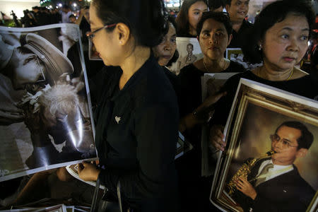 Well-wishers hold pictures of the late King Bhumibol Adulyadej on the last day the authorities allow people to pay their respect to the late king in the throne hall in Bangkok, Thailand, October 5, 2017. REUTERS/Athit Perawongmetha