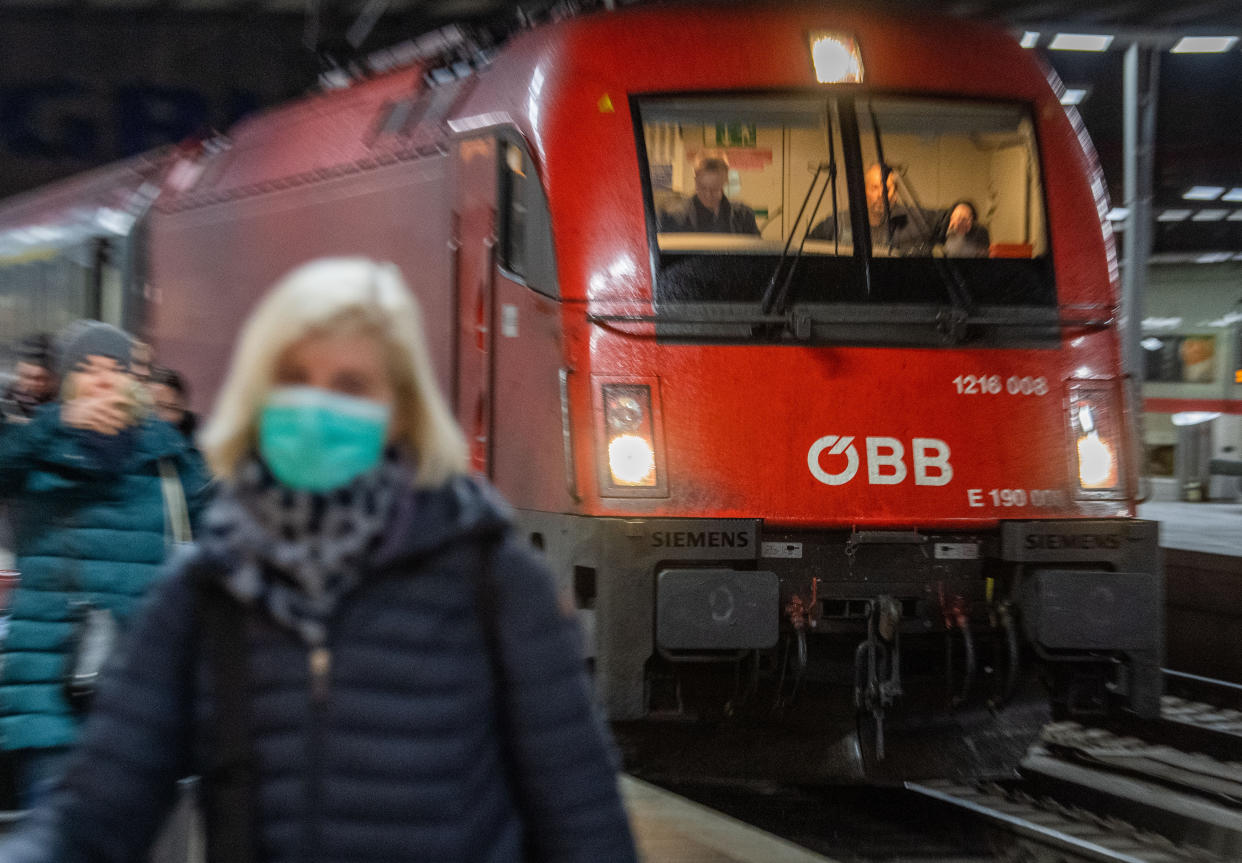 24 February 2020, Bavaria, Munich: A woman wearing a breathing mask walks in front of the Eurocity train along the main station in Munich. The train, stopped at the Brenner Pass for fear of the corona virus, arrived in Munich early Monday morning, several hours late. Photo: Lino Mirgeler/dpa (Photo by Lino Mirgeler/picture alliance via Getty Images)