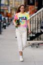 <p>In a multicolor tie-dyed t-shirt, cropped creme pants, white sneakers, sunglasses, multi-stand pearl necklace, and a black handbag. </p>