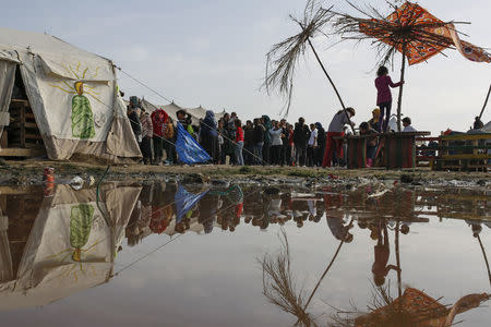 People queue to receive free food at a makeshift camp for migrants and refugees at the Greek-Macedonian border near the village of Idomeni, Greece, April 6, 2016. REUTERS/Marko Djurica