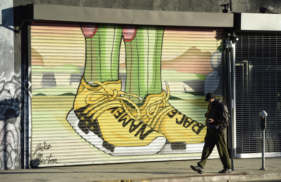 This Jan. 9, 2019 photo shows a pedestrian walking past a mural by artist Jake Merten inspired by the "Dragon Ball" anime series in Los Angeles. "Dragon Ball” is a revered anime that has influenced pop culture for years, earning praise from the likes of Michael B. Jordan, Ronda Rousey and Chris Brown, showing up in end zone celebrations and even at the Macy’s Thanksgiving Day Parade. With the new film "Dragon Ball Super: Broly" releasing this week in the U.S., the franchise’s popularity with its famous and non-famous fans is likely to grow. (AP Photo/Chris Pizzello)