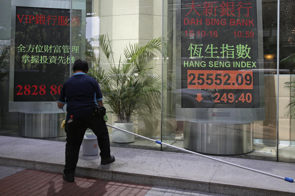 A worker stands in front of an electronic board showing Hong Kong share index outside a bank In Hong Kong, Monday, Oct. 15, 2018. Asian stocks slipped Monday, as investor worries continued about global trade tensions and prospects for economic growth. (AP Photo/Kin Cheung)