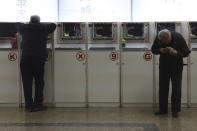 Chinese men monitor stock prices at a brokerage in Beijing, Friday, Oct. 19, 2018. Asian stock markets sank Friday after Wall Street declined on losses for tech and industrial stocks and Chinese economic growth slowed. (AP Photo/Ng Han Guan)