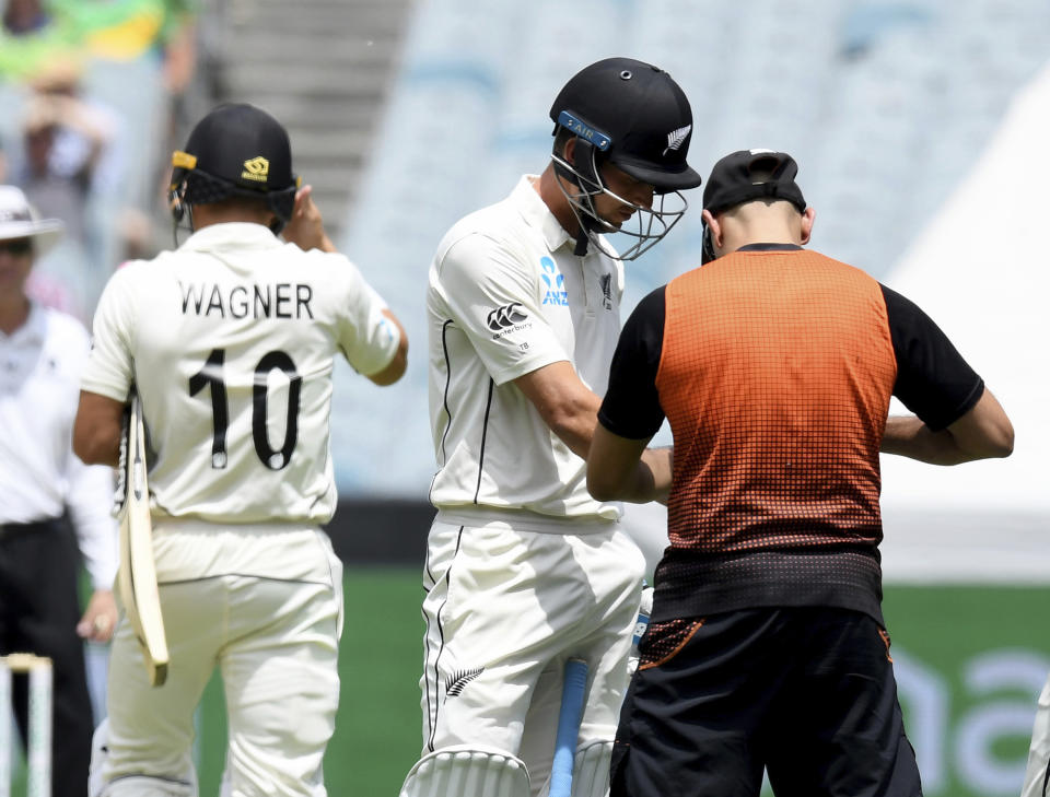 New Zealand's Trent Boult, center, has his hand attended to during their cricket test match against Australia in Melbourne, Australia, Saturday, Dec. 28, 2019. (AP Photo/Andy Brownbill)