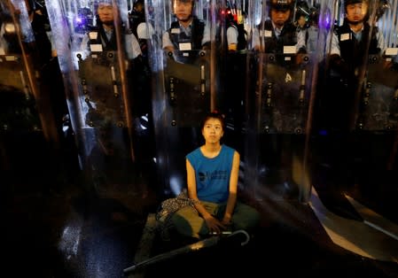 FILE PHOTO: Demonstrator sits down in front of riot police during a demonstration to demand authorities scrap a proposed extradition bill with China, in Hong Kong