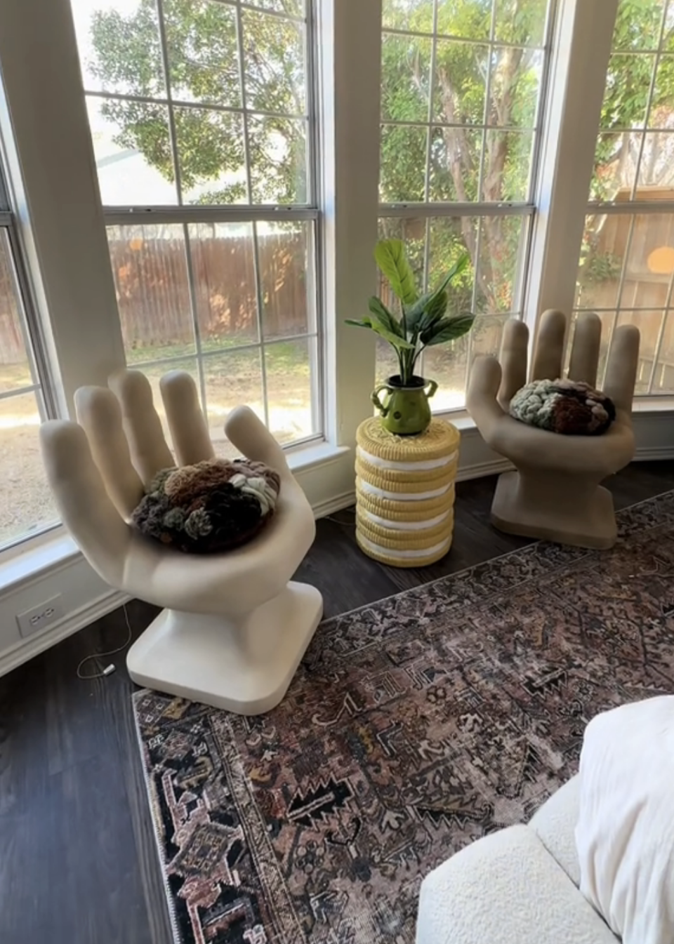 Giant hand chairs next to a table that looks like stacked giant golden Oreos stacked