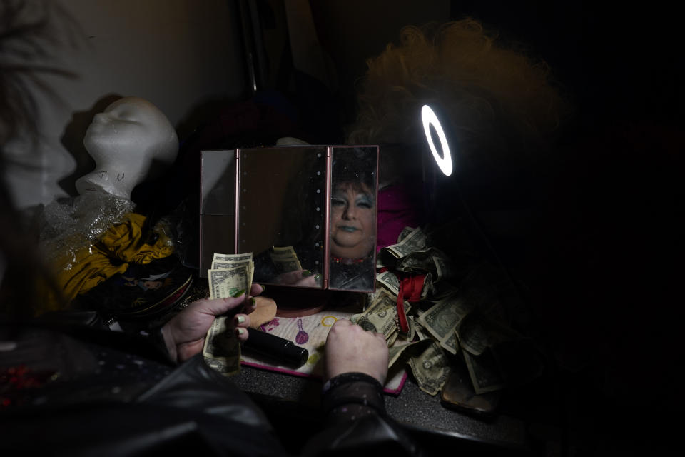 Drag queen Alexus Daniels, dressed as Tina Turner, is reflected in a makeup mirror as she counts tips in the dressing area during the "Spring Fever Drag Brunch," Sunday, March 26, 2023, at the Kulpmont Winery in Kulpmont, Pa. (AP Photo/Carolyn Kaster)