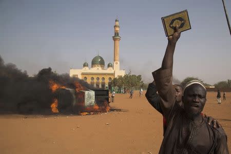 A man holds a copy of the Koran during a protest against Niger President Mahamadou Issoufou's attendance last week at a Paris rally in support of French satirical weekly Charlie Hebdo, which featured a cartoon of the Prophet Mohammad as the cover of its first edition since an attack by Islamist gunmen, in Niamey January 17, 2015. REUTERS/Tagaza Djibo