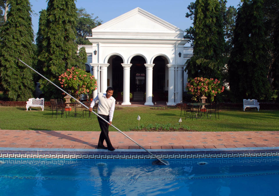 In this photo taken Nov. 29, 2012, a staff member cleans the pool of Thengal Manor, the gracious residence in Assam of one of India’s most prominent tea dynasties in Jorhat, India. The manor, featuring superb food, service and serenity, was opened to guests in 2000. Others in India and Sri Lanka offer visitors a chance to sample the lifestyle of tea planters and, of course, their brews. (AP Photo/Denis Gray)