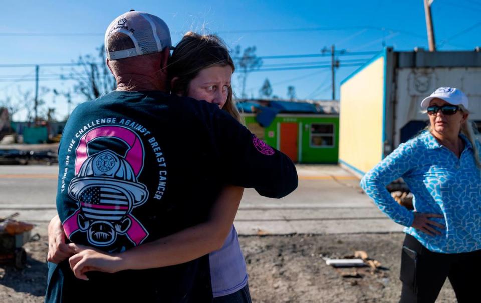 Savannah Lynch, 16, hugs her father, John Lynch, 59, and her mother, Tammey, 55, watches on Thursday, Sept. 29, 2022, in Matlacha, Fla. Hurricane Ian made landfall on the coast of South West Florida as a category 4 storm Tuesday afternoon leaving areas affected with flooded streets, downed trees and scattered debris.