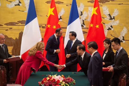 Prime Minister Edouard Philippe speaks to China's Premier Li Keqiang as French Justice Minister Nicole Belloubet shakes hands with an unidentified person during a signing ceremony at the Great Hall of the People in Beijing, China June 25, 2018. Fred Dufour/Pool via REUTERS