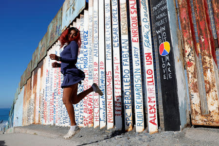 Yaderin Alexandra Banias, a migrant from Honduras, part of a caravan of thousands traveling from Central America en route to the United States, poses in front of the border wall between the U.S. and Mexico in Tijuana, Mexico, November 23, 2018. REUTERS/Kim Kyung-Hoon