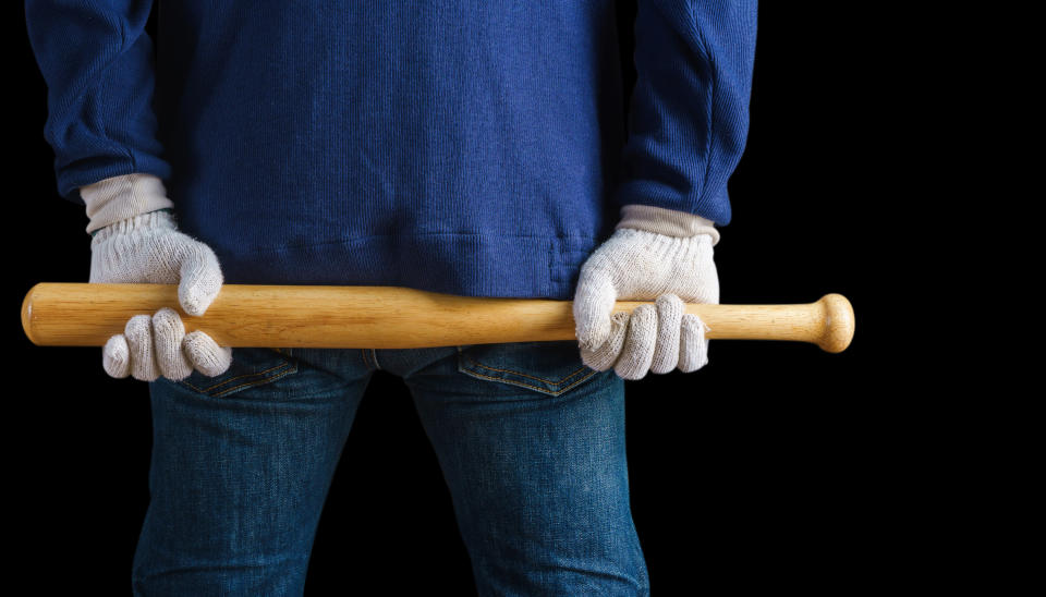 man holding baseball bat behind his back