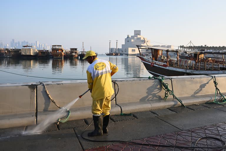 En Qatar ultiman detalles para la puesta a punto; un hombre limpia una de las veredas de la Corniche, a metros del Museo del Arte Islámico