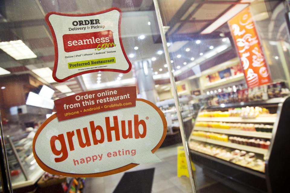 FILE - This April 4, 2014 file photo shows signage for food delivery services GrubHub and Seamless displayed on the door of a restaurant in New York. The growing options for outsourcing meal planning, grocery shopping and cooking can be called time-saving blessings or culture-destroying curses. In the end, they're probably a complicated mix of both. (AP Photo/Mark Lennihan, File)