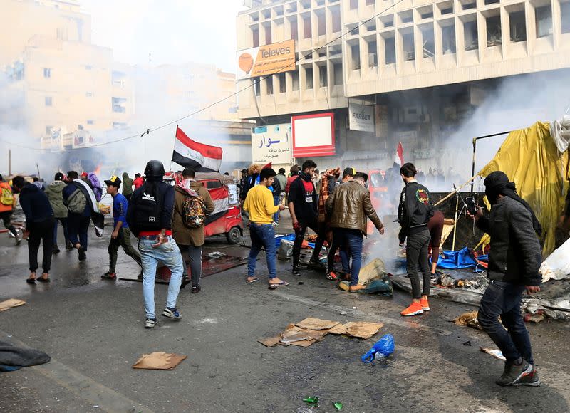 Demonstratos are seen amongst smoke rising from burning tents as Iraqi security forces raid at Tahrir Square during ongoing anti-government protests in Baghdad