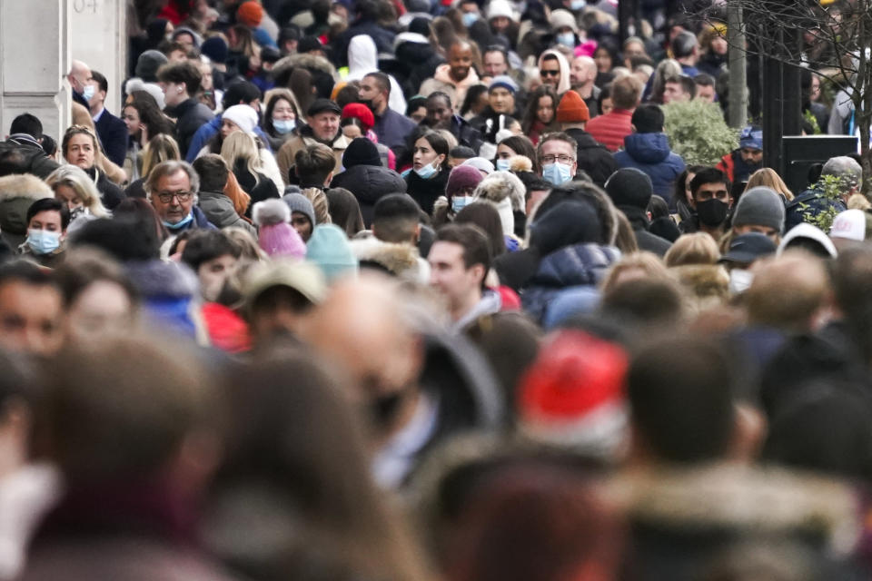 People, some wearing face masks, walk in Regent Street, in London, Sunday, Nov. 28, 2021. Britain's Prime Minister Boris Johnson said it was necessary to take "targeted and precautionary measures" after two people tested positive for the new variant in England. He also said mask-wearing in shops and on public transport will be required. (AP Photo/Alberto Pezzali)