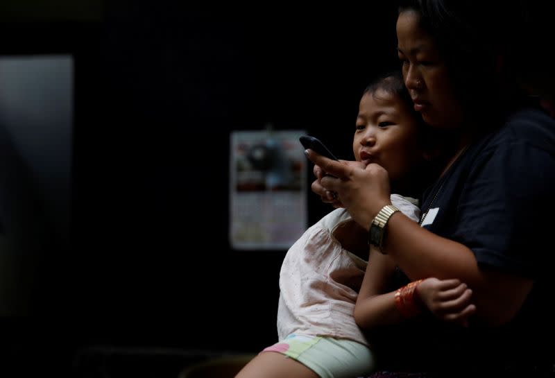 Nepali housewife Shiba Kala Limbu uses her mobile phone while her five-year-old daughter Masim Limbu sits on her lap in Kathmandu