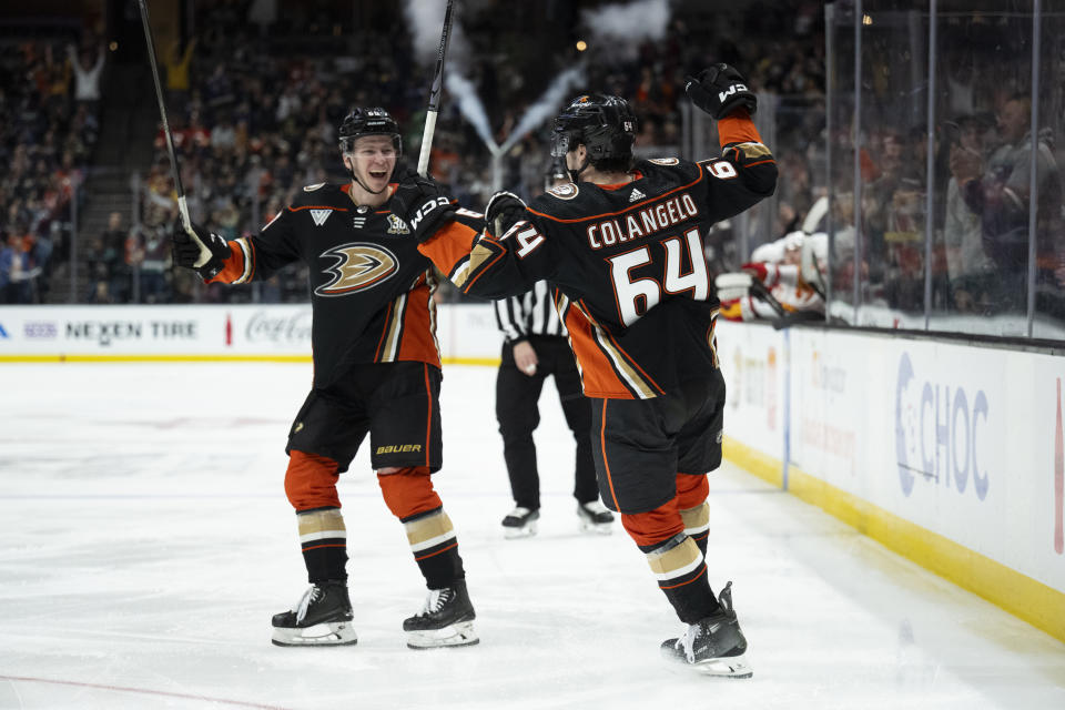 Anaheim Ducks forward Sam Colangelo (64) celebrates his first NHL goal with defenseman Jackson LaCombe (60), during the third period of the team's NHL hockey game against the Calgary Flames, Friday, April 12, 2024, in Anaheim, Calif. (AP Photo/Kyusung Gong)
