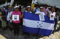 Women from the "Caravana de Madres Centroamericanas" (Caravan of Central American Mothers), hold a Hondurian flag and photos of missing migrants after arriving at Tecun Uman on a raft, as they head for the Suchiate river in the border city of Tecun Uman, north of Guatemala, December 18, 2013. According to the organizers, the group which is made up of relatives of people who went missing while making their way to the U.S. went to Mexico in the last two weeks to demand that the governments of Mexico and Central America stop the kidnappings and crimes committed by organised criminal groups against migrants. REUTERS/Jorge Dan Lopez (MEXICO - Tags: CRIME LAW SOCIETY IMMIGRATION POLITICS)