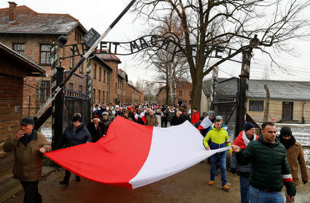 Far right activists walk past the "Arbeit Macht Frei" gate at the former Nazi German concentration and extermination camp Auschwitz, as they pay tribute to Polish victims, during the ceremonies marking the 74th anniversary of the liberation of the camp and International Holocaust Victims Remembrance Day, in Oswiecim, Poland, January 27, 2019. REUTERS/Kacper Pempel