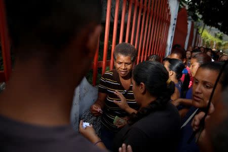 A woman receives a numbered ticket while she queues to try and buy food outside a market in Caracas, Venezuela March 17, 2017. REUTERS/Carlos Garcia Rawlins