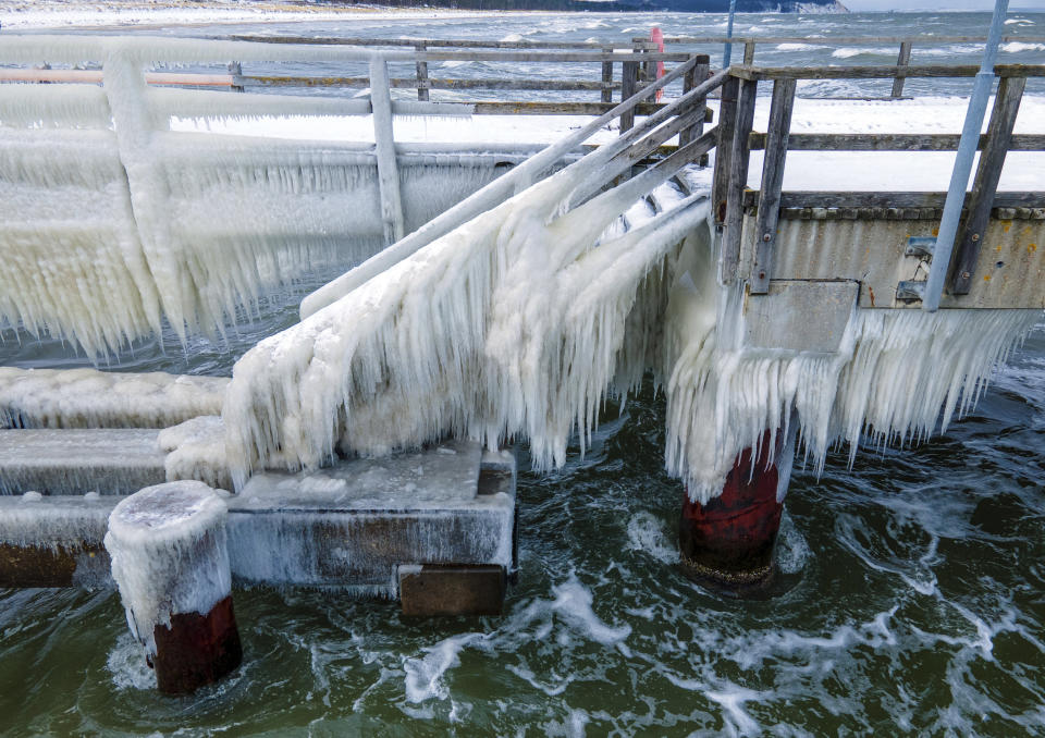 A thick layer of ice has formed at temperatures of minus five degrees on the pier on the island of Ruegen, Germany, Thursday, Feb.11, 2021. The bridge is closed to pedestrians because of the icing. (Jens Buettner/dpa via AP)