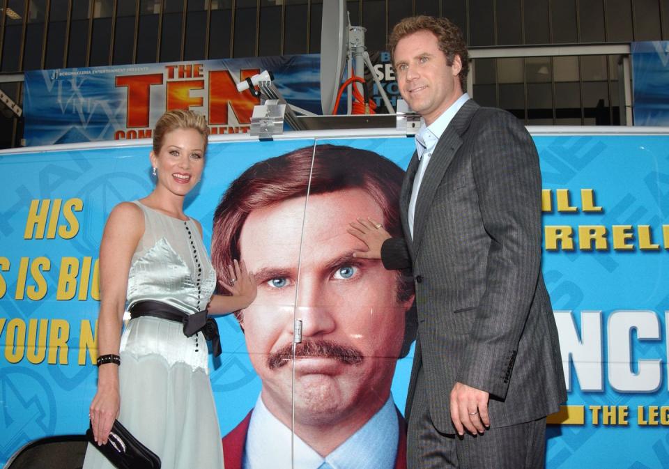 christina applegate and will ferrell standing in front of a poster for their film anchorman at a premiere event