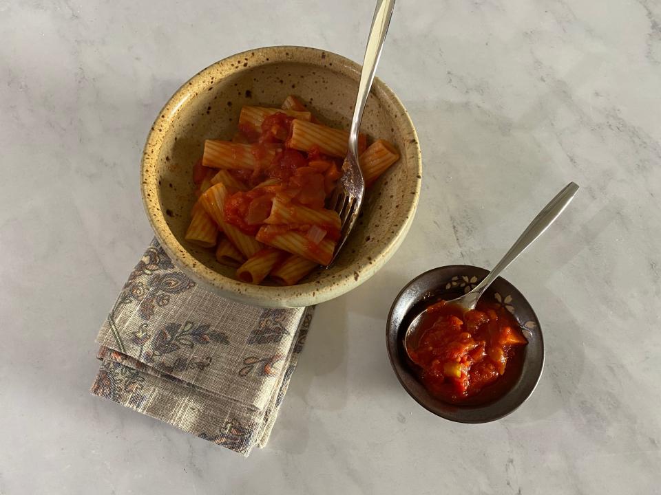 Bowl of pasta with marinara sauce next to a smaller bowl of marinara