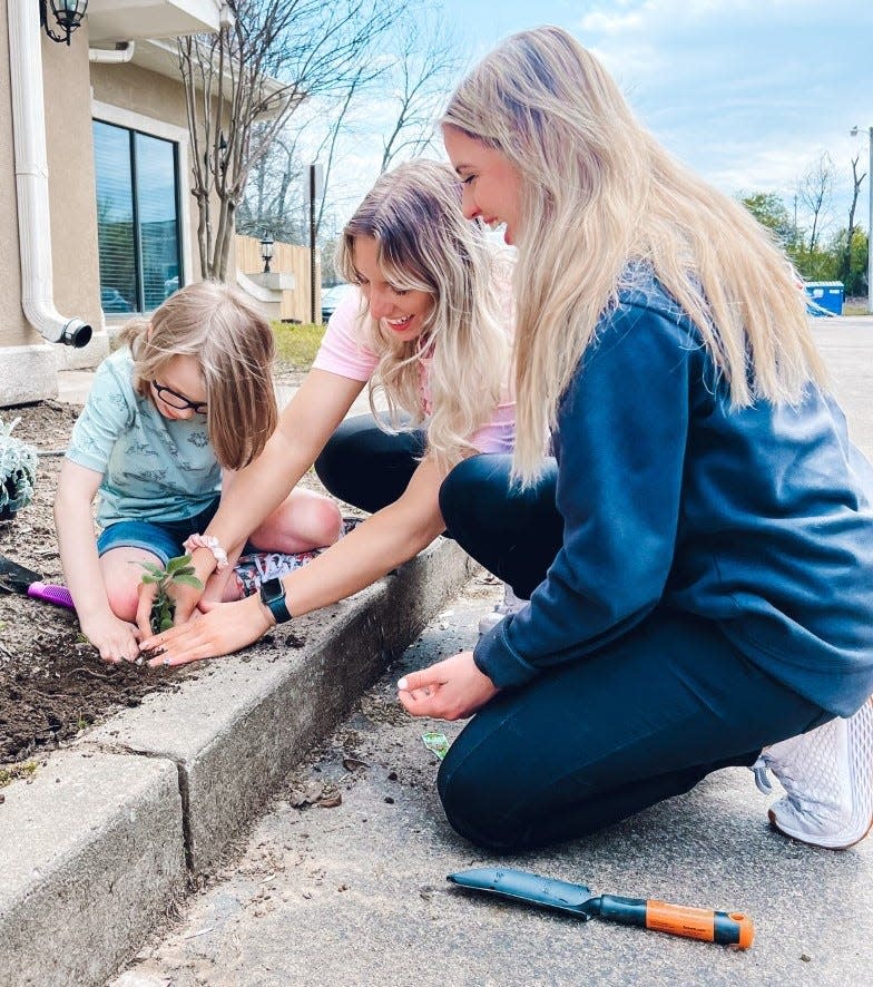 Titus Bryant works in a flower bed with Hope 4 Autism therapists, Kayli Sossamon and Abby Ross in Fort Smith Thursday, March 31, 2023.