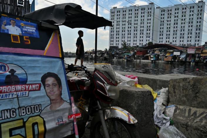 A child stands next to campaign posters on display in a slum area in Manila on May 4, 2022.<span class="copyright">CHAIDEER MAHYUDDIN/AFP via Getty Images</span>