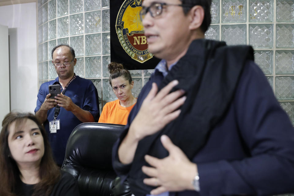 American Jennifer Erin Talbot, center rear, from Ohio looks as National Bureau of Investigation - International Airport Investigation Division chief Atty. Manny Dimaano shows a bag which Talbot allegedly used to carry a baby during a press conference in Manila, Philippines on Thursday, Sept. 5, 2019. The NBI said the 43-year-old Talbot was arrested at the Ninoy Aquino International Airport yesterday for trying to bring out of the country a 6-day old Filipino baby without proper travel documents. (AP Photo/Aaron Favila)