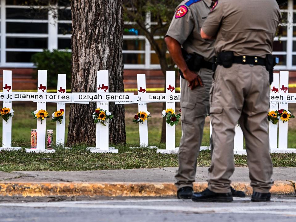 Police officers stand near a makeshift memorial for the shooting victims at Robb Elementary School in Uvalde, Texas, on May 26, 2022.