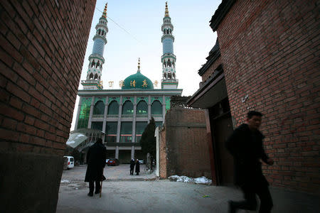 A man runs in front of a mosque at dusk as evening prayers are underway inside, in China's Linxia, Gansu province, home to a large population of ethnic minority Hui Muslims, February 2, 2018. Picture taken February 2, 2018. REUTERS/Michael Martina