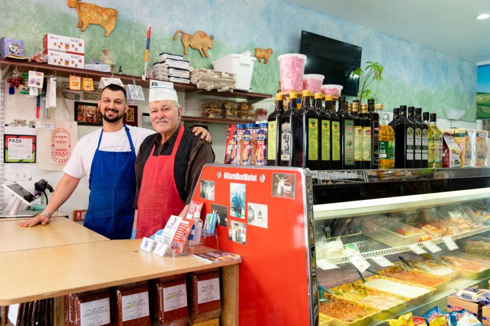 A young man and his father stand behind the counter at their market.