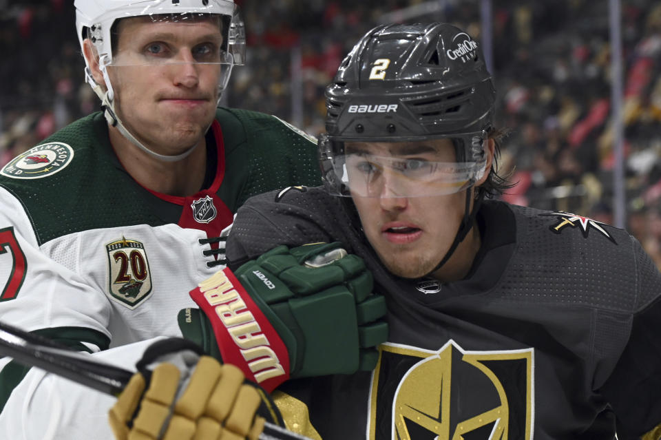 Minnesota Wild center Nick Bjugstad (27) and Vegas Golden Knights defenseman Zach Whitecloud (2) battle for the puck during the third period of Game 1 of a first-round NHL hockey playoff series Sunday, May 16, 2021, in Las Vegas. (AP Photo/David Becker)