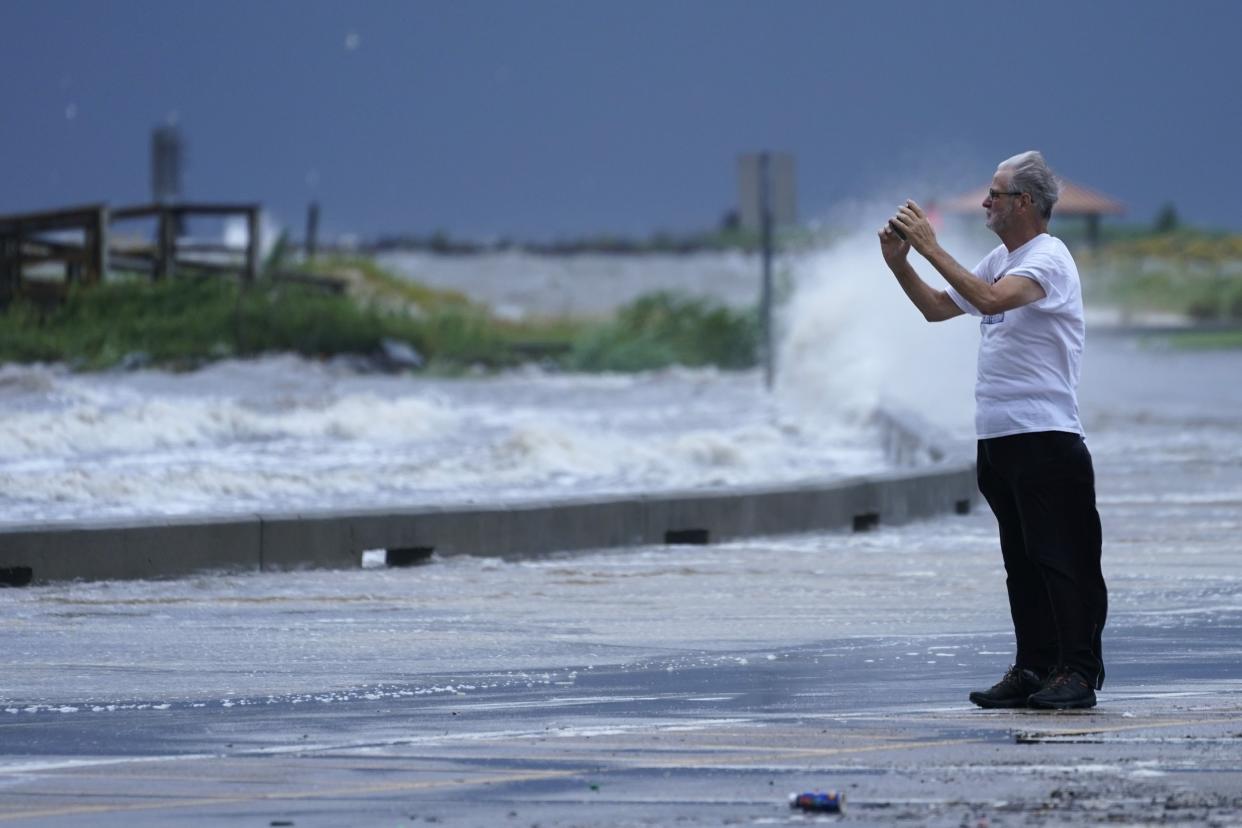 A spectator photographs floodwaters at the Port Gulfport Marina as he watches the arrival of Hurricane Ida on Sunday, Aug. 29, 2021, in Gulfport, Miss.