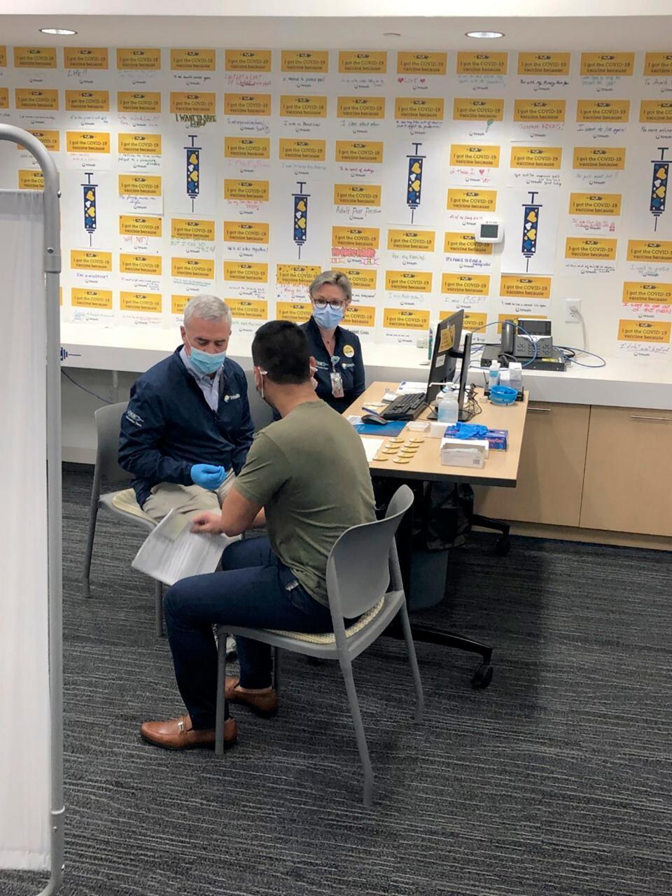 U.S. Rep. Brad Wenstrup, R-Ohio, left, and a doctor prepare to administer a COVID-19 vaccine to Eli Livingston in March 2021 in Norwood.