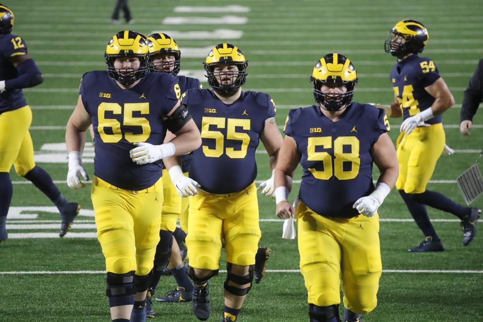 Michigan Wolverines offensive lineman Zak Zinter (65), Nolan Rumler (55) and Zach Carpenter (58) warm up before the game vs. Wisconsin at Michigan Stadium in Ann Arbor, Nov. 14, 2020.