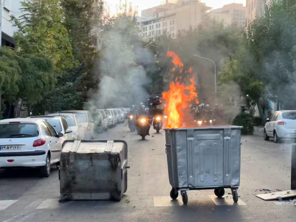 In this photo, a trash bin is burning as anti-riot police arrive amid protests in Iran on Tuesday, Sept. 20, 2022.