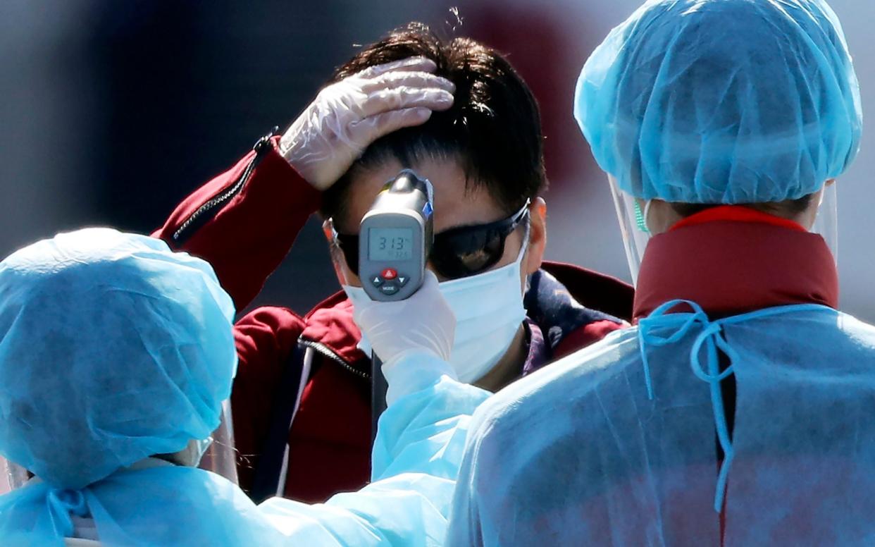 An official measures the temperature of the foreign passengers disembarking from the quarantined Diamond Princess cruise ship - AP